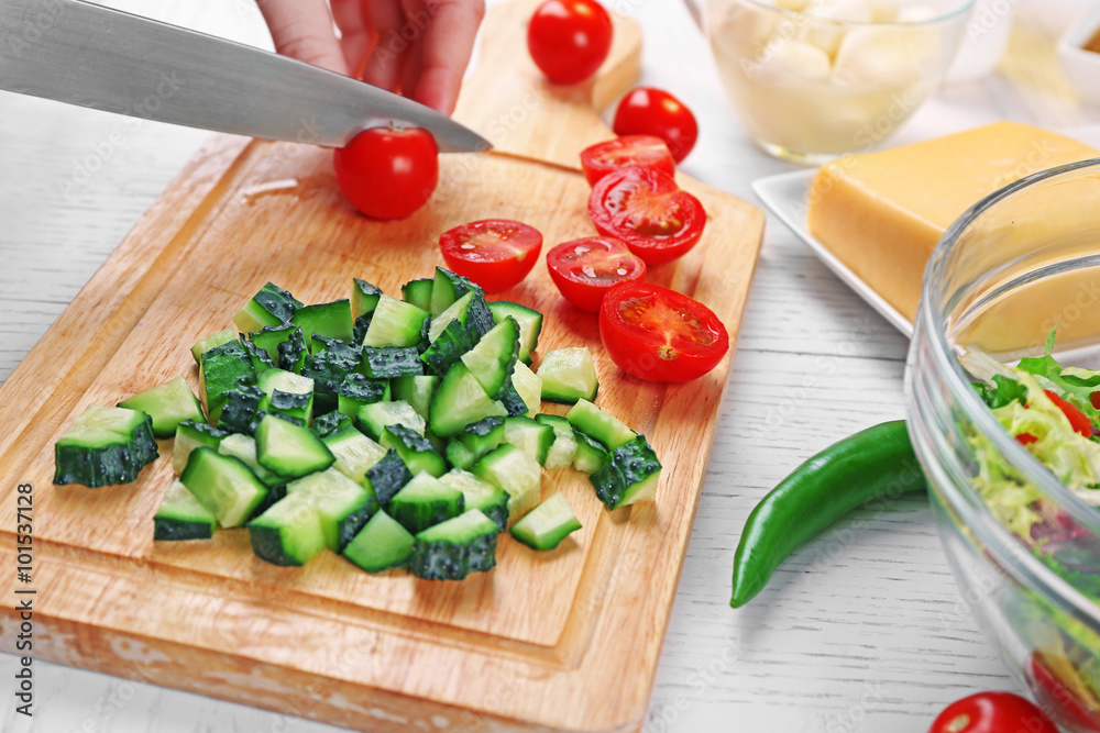 Female hands cutting vegetables for salad, at kitchen