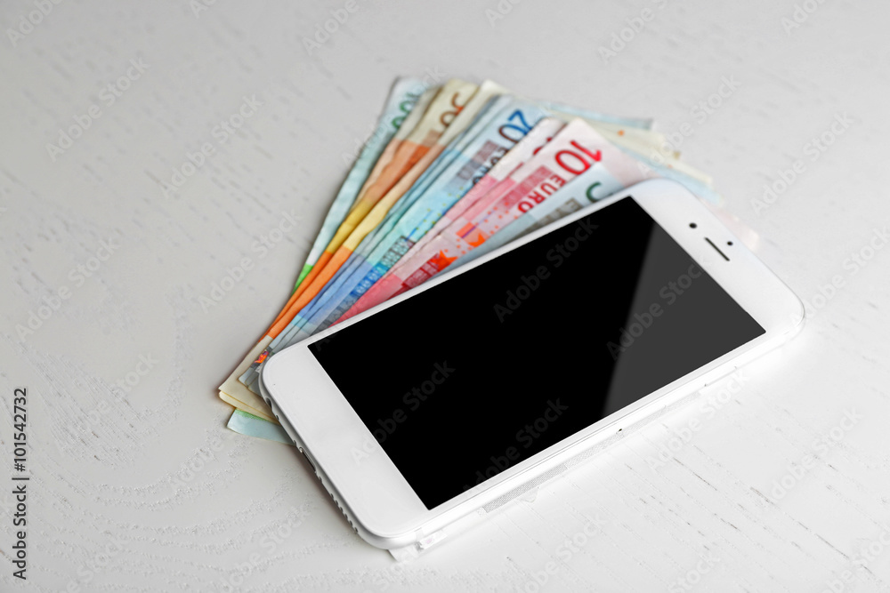 Smart phone on euro banknotes over light table. Internet earning concept