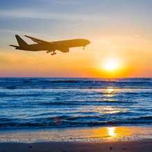 Airplane Over A Sea Coast Sunset