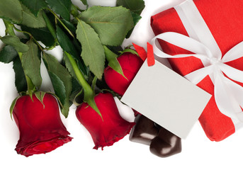 Red present box with ribbon, red roses, postcard and candies