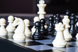 white pawn surrounded by black chess pieces on a chess board