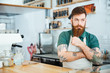 Handsome pensive man barista touching his beard and thinking