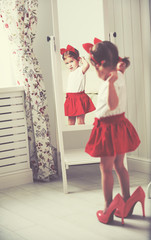 Wall Mural - little girl child fashionista looking in the mirror at home