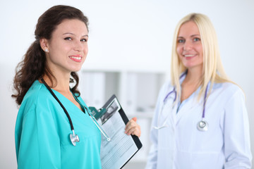 Two confident friendly female doctors sitting at the table and listen to the patient's history . Medical and health care concept