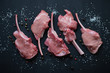 Top view of raw bobby veal rack steaks on a black wooden surface