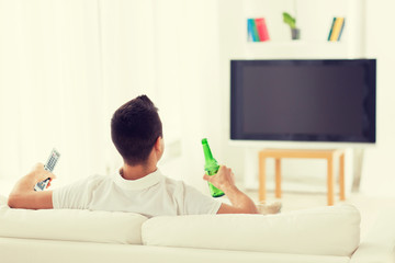 Wall Mural - man watching tv and drinking beer at home