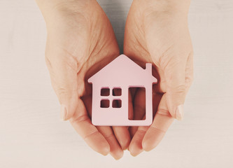 Sticker - Female hands with model of house on light background