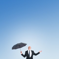 Poster - Composite image of businessman sheltering under black umbrella