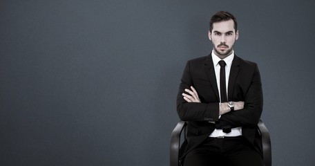 Poster - Composite image of serious businessman sitting with arms crossed