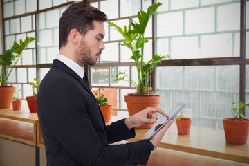 Poster - Composite image of concentrated businessman touching his tablet