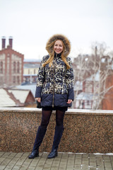 Wall Mural - Happy young blonde woman on the background of a winter park