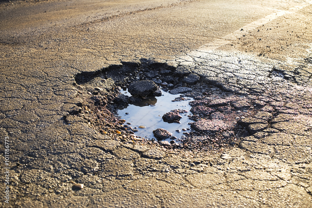 A road damaged by rain and snow, that is in need of maintenance. Broken asphalt pavement resulting in a pothole, dangerous to vehicles.
 - obrazy, fototapety, plakaty 