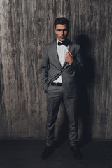 Wall Mural - Confident man with a bow-tie standing on the grey background