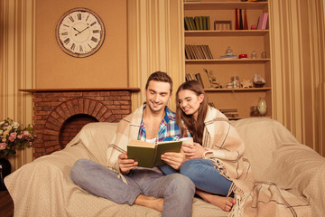 Canvas Print - Happy couple in love with plaid reading book on the sofa