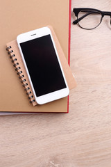 Sticker - top view smartphone on book and glasses on wooden background