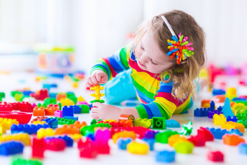 Wall Mural - Little girl playing with colorful toy blocks