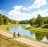 Fototapeta Na sufit - Young Happy Couple Riding Bicycles by the River