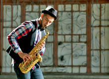 Man With Saxophone Outside Near The Brick Wall