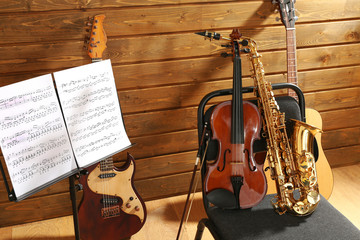 Wall Mural - Musical instruments on a chair and note holder against wooden background