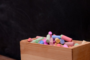 Wall Mural - Wooden box of coloured chalk in front of blackboard