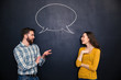 Happy couple talking over chalkboard background with drawn dialogue