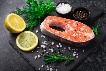 Wall Mural - Raw salmon steak with salt, lemon and herb on the dark background