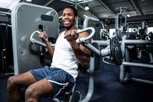 Smiling Muscular Man Using Exercise Machine 