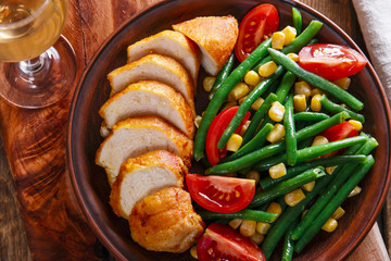 grilled chicken breast  with green beans and tomato on a plate