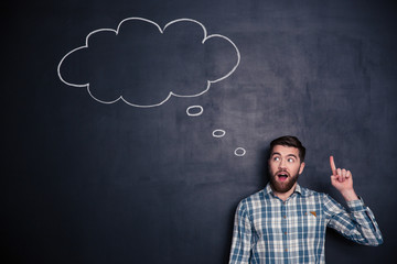 Canvas Print - Inspired man pointing up and having an idea over blackboard