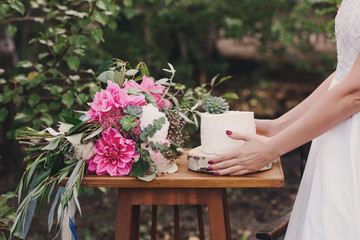 Wedding cake and bouquet of flowers, the bride's hands, baking, cake decoration