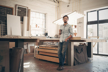 Young designer in his workshop with a cup of coffee