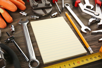 Wall Mural - Different kinds of tools with a notebook on wooden background