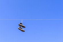 Old Gym Shoes On A Wire Against The Blue Sky