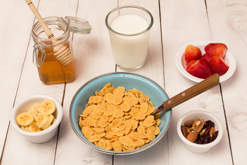 Corn flakes ceral breakfast milk, strawberry , honey, and nuts