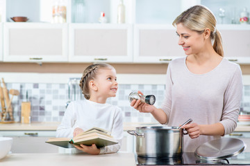 Positive mother and her daughter cooking 