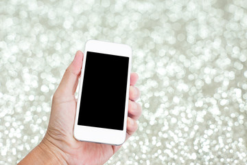 Hand holding mobile phone with festive silver glitter background