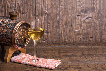 Copper forged barrel and a glass of wine is stand on a old table