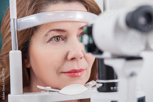 Cuadros en Lienzo Cheerful lady having eye examination in oculist office