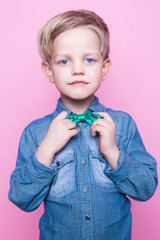 Wall Mural - Young beautiful boy with blue shirt and butterfly tie. Studio portrait over pink background