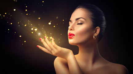 beauty young woman blowing magic dust with golden hearts