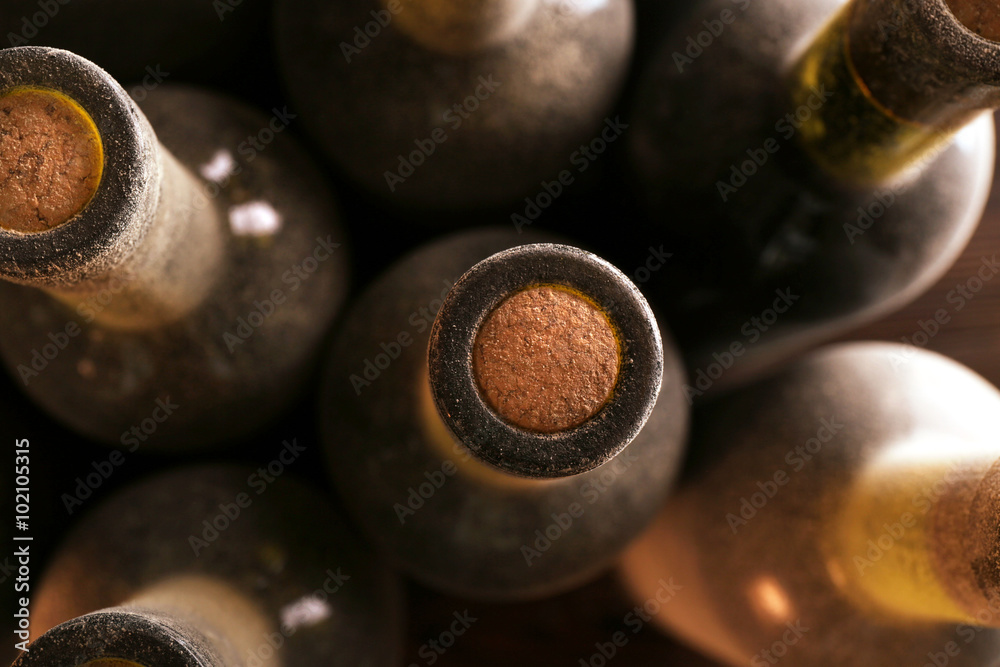 Stacks of dusty wine bottles on wooden background, upside view. Close up
