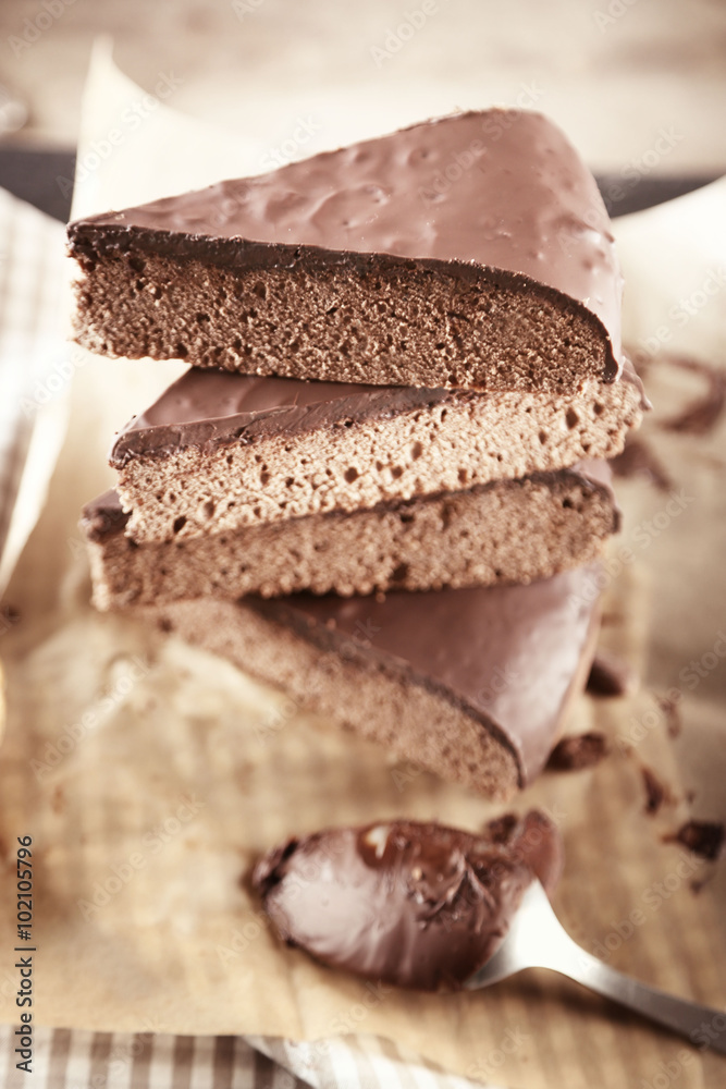 Pieces of frosting chocolate cake on parchment paper