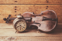 Antique Clock And Old Violin Over Vintage Wooden Table