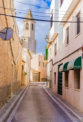 Fototapete - Narrow street with an church spire at background