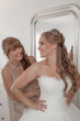 © godfer - bride and mother dressing on wedding day.
