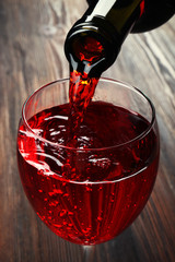 Poster - Pouring red wine on wooden background