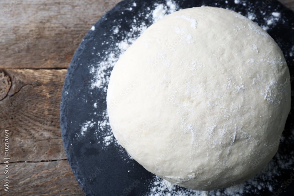 Fresh prepared dough on a wooden board, close up