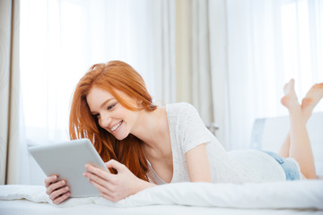 Sticker - Smiling woman using tablet computer on the bed