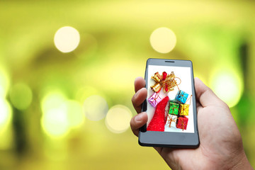 Hand hold and touch screen smart phone, tablet,cellphone on male bantam isolated on Christmas gift box green blur background.