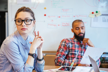 Pensive woman sitting and thinking while her male colleague reading